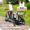 Vrouw fietst met een beige hondenkar met een bordercolliër erin op een landweg.