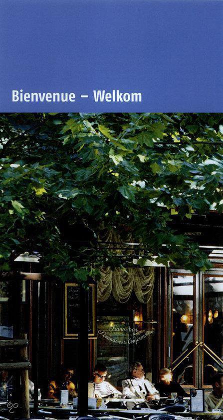Een terras met groene bomen en mensen die aan tafels zitten.