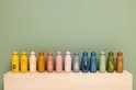 Twaalf roze, blauwe, groene en gele drinkflessen met dierenprints, zoals een leeuw, bij, hond, beer en konijn.