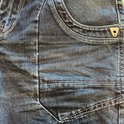 Detail van een blauwe jeans met stone wash used look en opvallende naden.