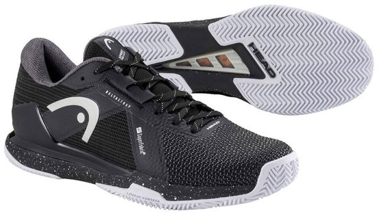 Zwarte tennis schoenen, één schoen van de zijkant, de ander van bovenaf met de zool zichtbaar. Witte spetters op de zool.