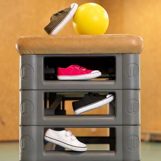 Rook- en donkergroene gymschoenen met klittenbandsluiting op een grijze opbergkast.