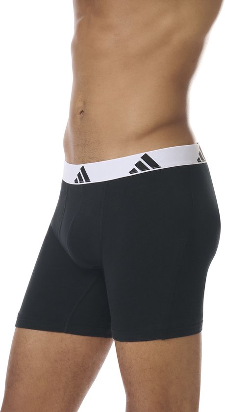 Zijkant van zwarte boxershorts met brede, witte Adidas-band met logo's.