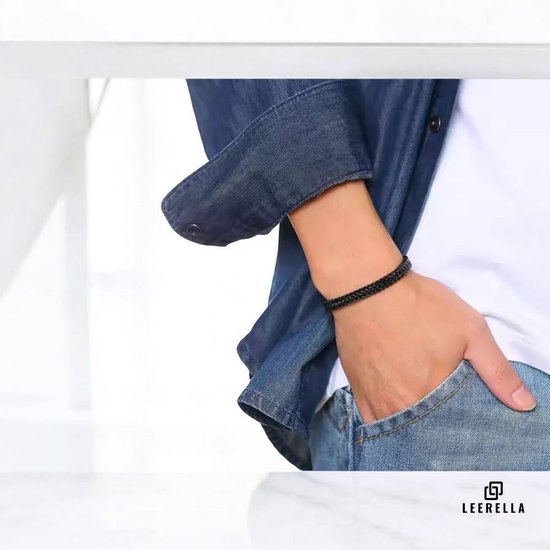Zwarte gevlochten armband om een pols van een man, met jeans en spijkerjack.