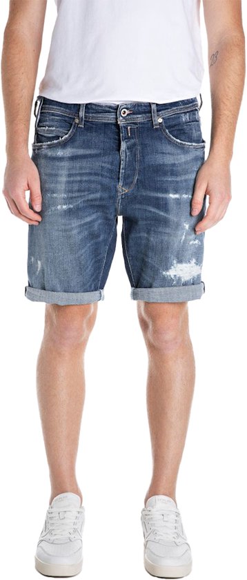 Short en denim bleu avec détails usés, bas de jambe retroussés et coupe droite, porté par un homme.