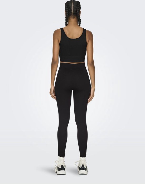 Zicht op de achterkant van een model met zwarte crop top en zwarte, nauwsluitende sportlegging met hoge taille.