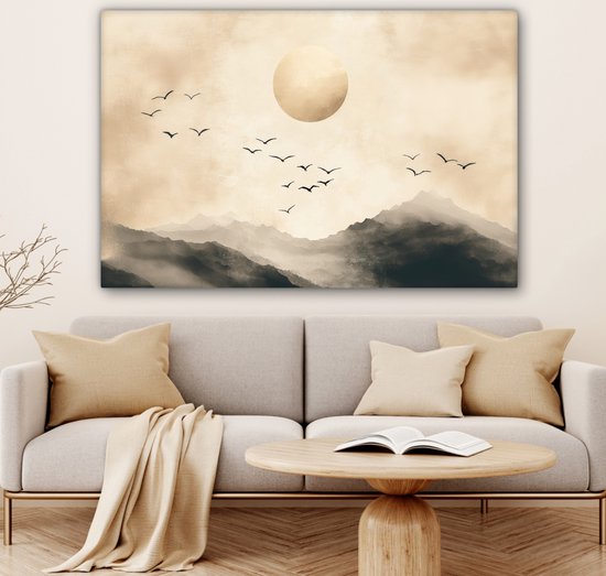 Toile paysage abstrait avec montagnes, grand cercle doré et oiseaux en vol, accrochée au-dessus d'un canapé avec un plaid.