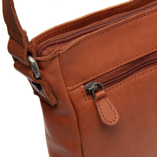 Detailopname van de ritssluiting en leren lussen van een bruine leren schoudertas.