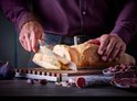 Een persoon snijdt een brood met een Wüsthof broodmes.