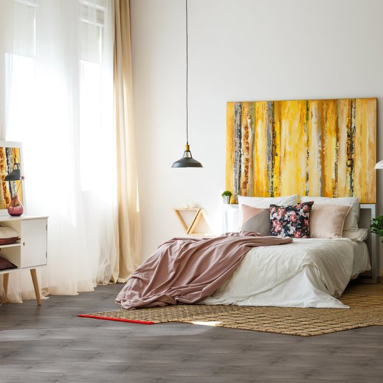 Slaapkamer met donkergrijze PVC-vloer, bed met roze deken en opvallend schilderij.