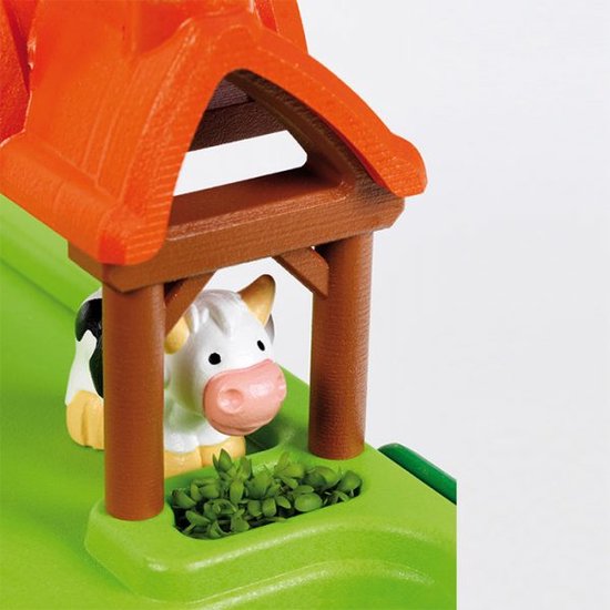 Close-up van de John Deere boerderij speeltafel: een zwart-wit koe staat onder een oranje dakje.