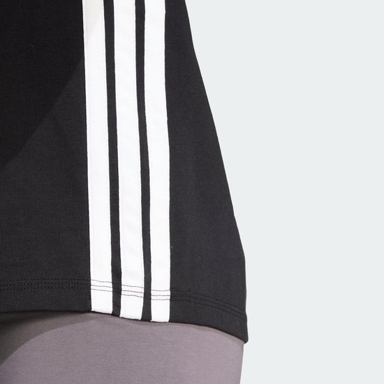 Detail van de zwarte dames t-shirt met de witte Adidas strepen op de zijkant.