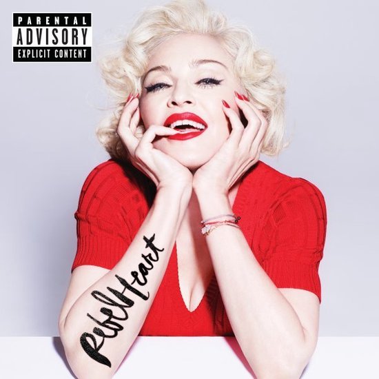 Madonna met blond krullend haar, rode lippen, rode top en "Rebel Heart" tatoeage op haar linkerarm. Ouders Advies Expliciet.