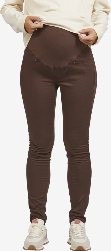 Gedetailleerde opname van de buik van een zwangere vrouw die de bruine legging omhoog trekt.