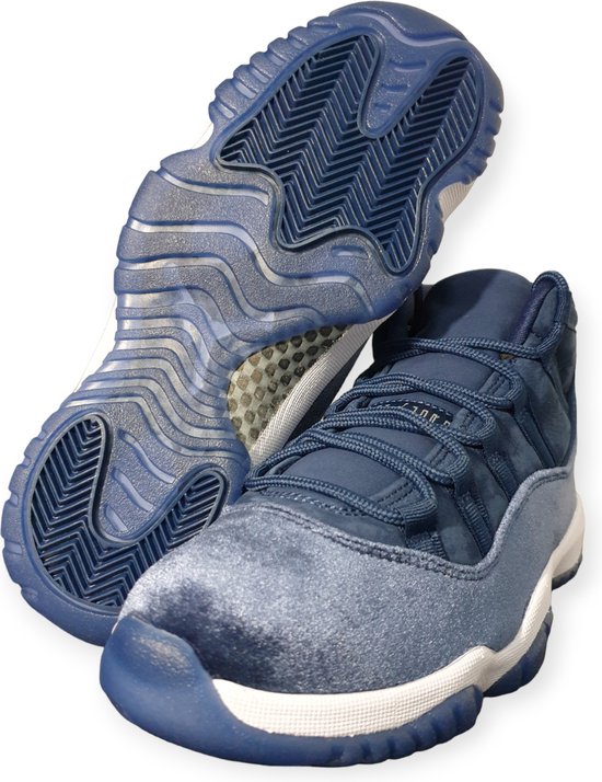 Donkerblauwe mid-top sneaker met witte zool en een opengewerkte zool. Een andere sneaker ligt ernaast.