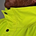 Detail van de kraag van een felgele jas, gesloten met twee zwarte drukknoppen. Grijze stiksels zichtbaar.