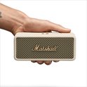 Een hand houdt een crème Marshall speaker vast.