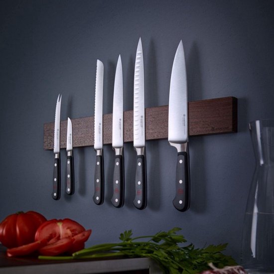 Set van zes Wüsthof CLASSIC messen aan een magnetische houten strip aan de muur. Groenten en salami ernaast.
