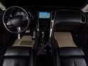 Interieur van een auto met beige automatten op de vloer en zwarte lederen stoelen.