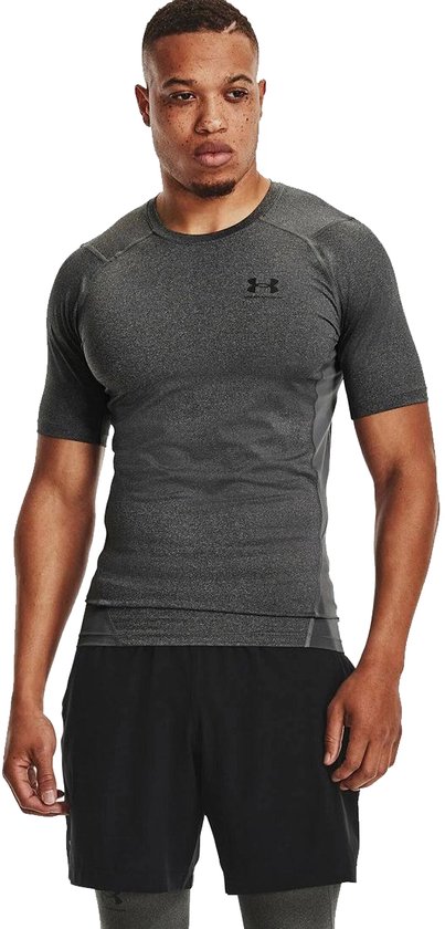 Man met donkergrijs, kort, nauwsluitend sportshirt met grijze panelen.