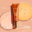 Lancaster Infinite Bronze getinte crème SPF30 naast petrischalen met hyaluronzuur en pigmenten.