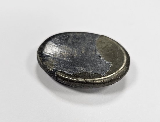 Een gladde, ovale, donkergrijze steen met glinsterende metalen accenten aan de linkerzijde.