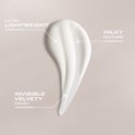 Een veeg ultra-lichtgewicht, melkachtige, fluweelzachte witte lotion op een zachtroze achtergrond.