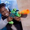 Jongen met veiligheidsbril speelt met groene speelgoedblaster met oranje details, camouflageprint en skull-motief.