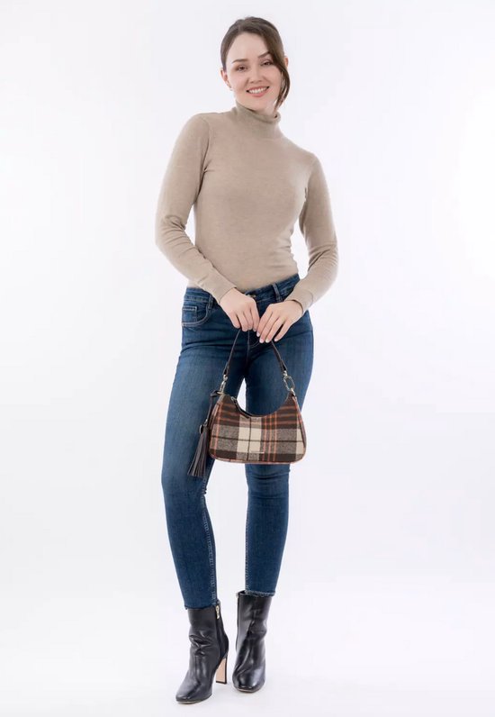 Vrouw in beige coltrui en spijkerbroek draagt bruine en beige ruitjes schoudertas met franjes.