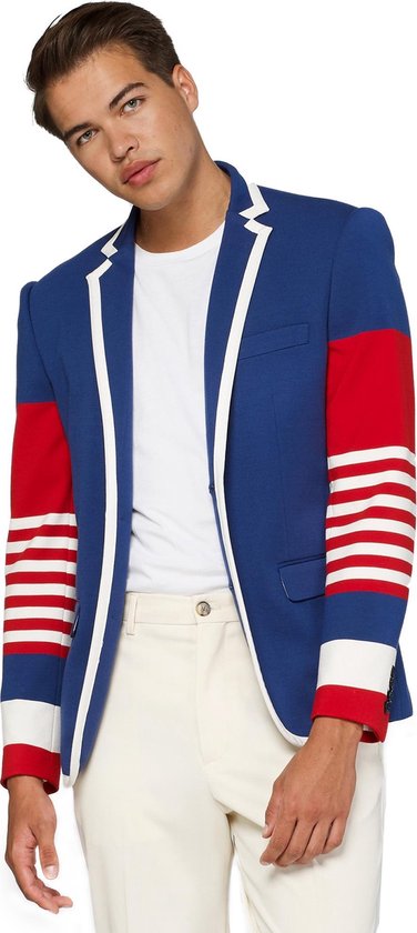 Model draagt een kobaltblauwe blazer met witte bies. De mouwen hebben rode en wit gestreepte delen.
