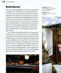 Een buitensalon met oranje stoelen en een verlichte maan aan de muur, bij een tuinhuisje.
