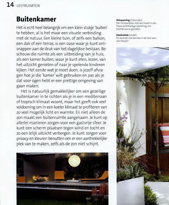 Een buitensalon met oranje stoelen en een verlichte maan aan de muur, bij een tuinhuisje.