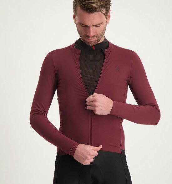 Man sluit een donkerrood wielershirt met lange mouwen over een zwart shirt met mesh-structuur.