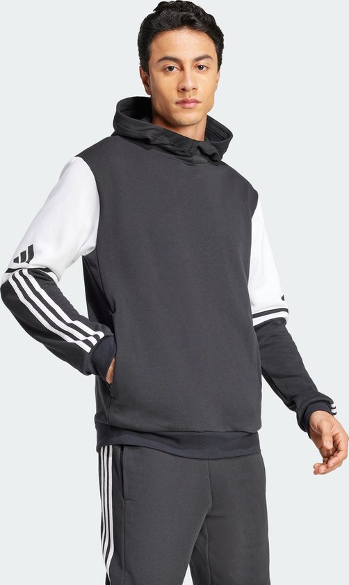 Man met een donkergrijs sweatshirt met witte mouwen en Adidas-strepen op de mouwen.