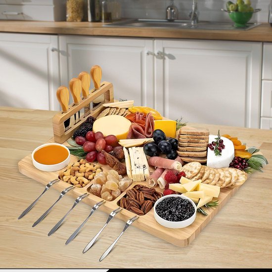 Houten borrelplank met diverse kazen, vleeswaren, fruit, noten, crackers en gedroogde abrikozen. Inclusief mesjes en schaaltjes.