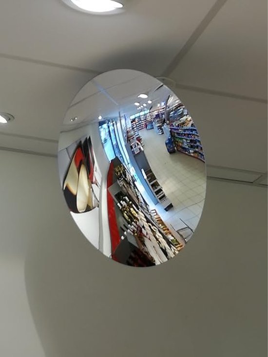 Bolle spiegel reflecteert een winkel met schappen vol producten en verlichting.