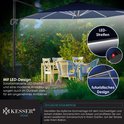 Donkerblauwe zweefparasol met LED-strips, verlicht een tuinmeubelset met vrienden, bij avond.