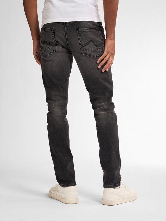 Man met rug naar de camera, draagt zwarte slim fit jeans met vintage wassing en twee achterzakken.