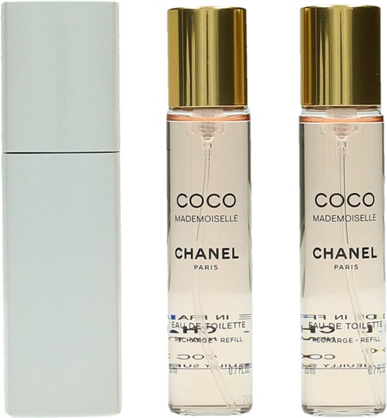 Drie flacons Coco Mademoiselle Eau de Toilette van Chanel met gouden dopjes, naast een zilverkleurige verstuiver.