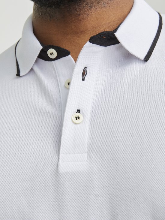 Detailopname van de kraag en knoopsluiting van een witte poloshirt met zwarte biezen.