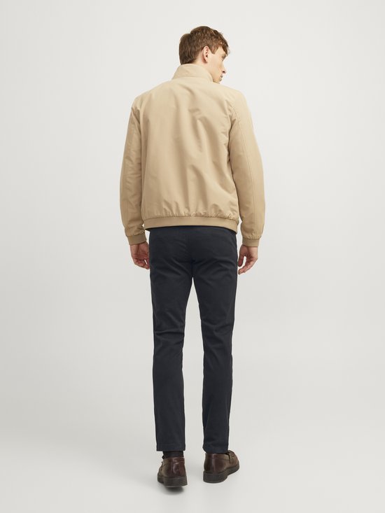 Man met beige bomberjack en zwarte chino, achterkant.