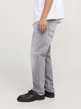 Lichtgrijze jeans, model van de zijkant met zwarte schoenen en een witte top.