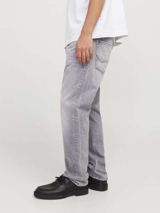 Lichtgrijze jeans, model van de zijkant met zwarte schoenen en een witte top.
