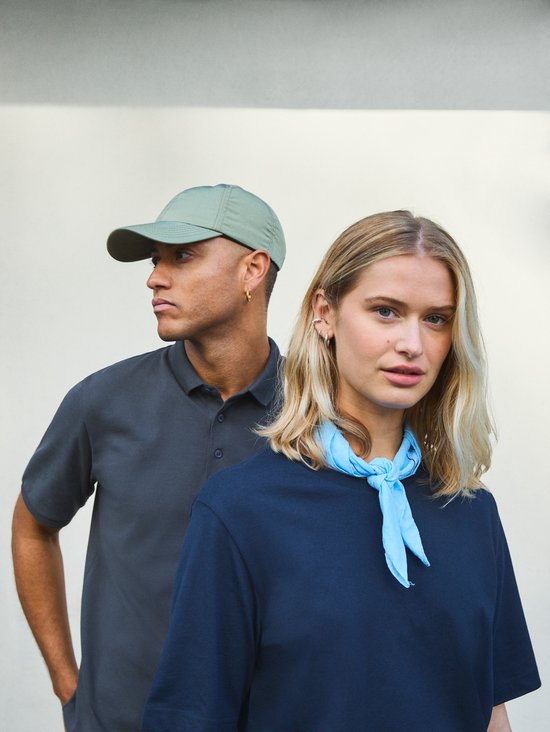 Man met groene pet en donkergrijs poloshirt, naast een vrouw met een donkerblauw shirt en lichtblauwe sjaal.