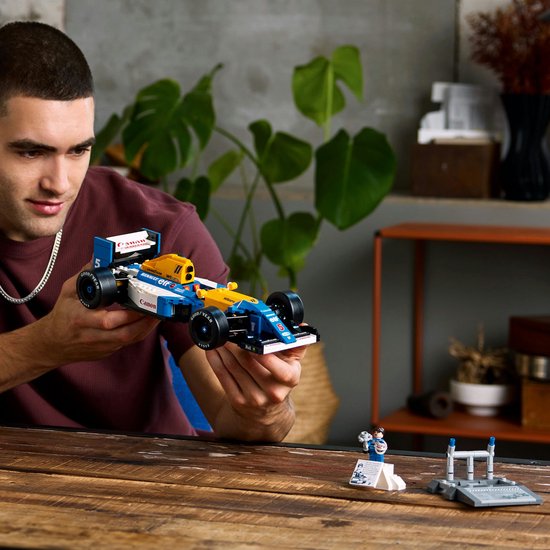 Man toont een LEGO Williams FW14B raceauto, met Nigel Mansell minifiguur op de achtergrond.