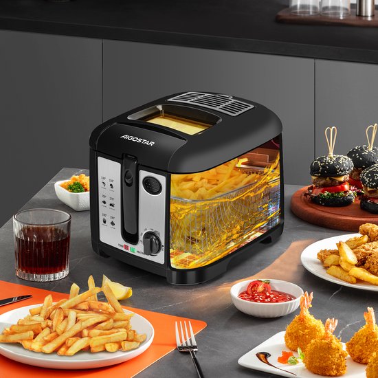 Zwarte Aigostar frituurpan met mand vol goudbruine frietjes en zicht op de olie. Aan tafel geserveerd met snacks.