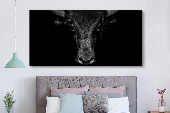 Toile noir et blanc d'un taureau au-dessus d'un lit, sur fond sombre.