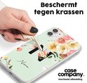 Lichtgroen telefoonhoesje met zwart initiaal 'N', bloemenprint en de tekst 'Nora'. Een hand met een sleutel laat het hoesje beschermd zien.
