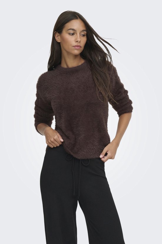 Model in bruine, harige trui met een zwarte broek met trekkoord.