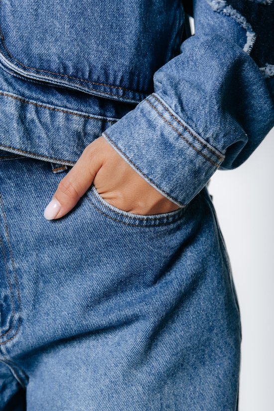 Close-up van een hand in de zak van een blauw denim jack.